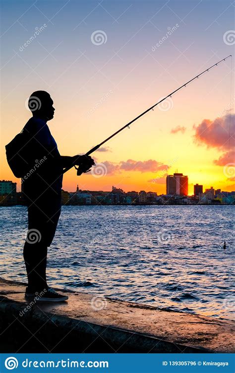 Silhouette Of A Man Fishing On The Bay Of Havana At Sunset Stock Photo