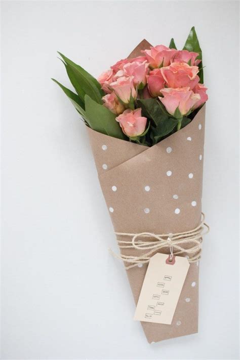 A Bouquet Of Flowers Wrapped In Brown Paper With A Tag Attached To It