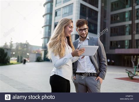 Business People Walking Outdoors And Using Phones Tablets Stock Photo