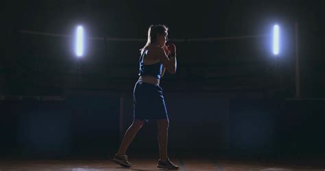 A Beautiful Woman Boxer Trains In A Dark Gym And Works Out Punches In