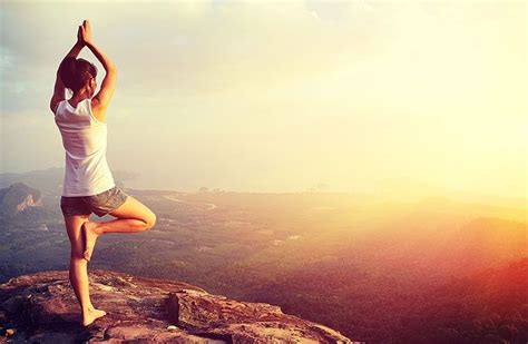 A Woman Doing Yoga On Top Of A Mountain With Her Hands Up In The Air