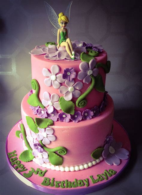 A Pink And Green Birthday Cake With A Tinkerbell Figure Sitting On The Top