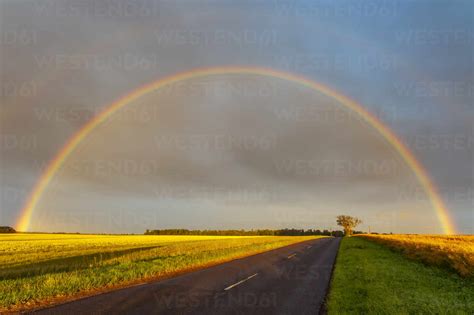 Double Rainbow Arching Over Empty Countryside Highway Stock Photo
