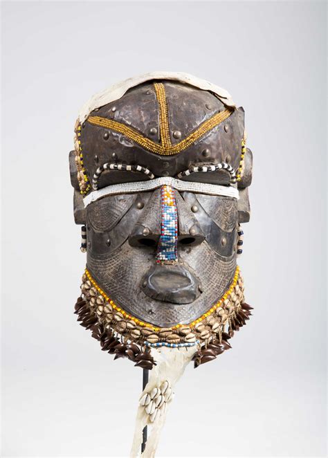 This kuba mask, known as mbwoom, is predominately made of carved wood with cowrie shell and bead embellishments. A Kuba Bwoom helmet mask