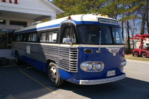 A Blue And White Bus Parked In Front Of A Building Next To A Red Truck