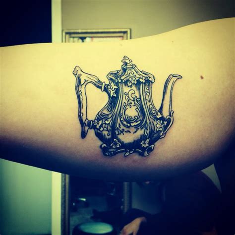 a black and white photo of a teapot tattoo on the right upper half of the arm