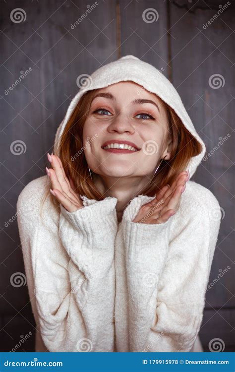 Young Beautiful Woman In White Sweater With Holding Her Hands Near Her
