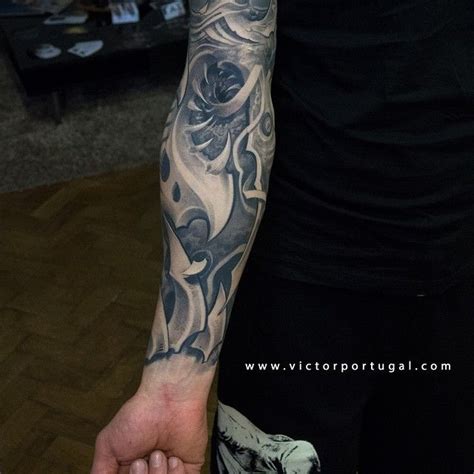 A Man With A Black And Grey Tattoo On His Arm Is Holding Something In