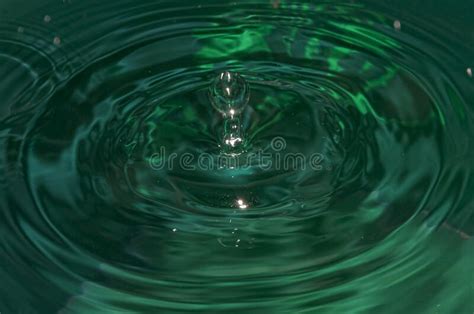 Closeup Shot Of A Water Drop And Ripples On Green Water Stock Photo