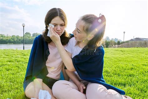 Crying Teenager Girl And Comforting Girlfriend Teenagers Sitting On