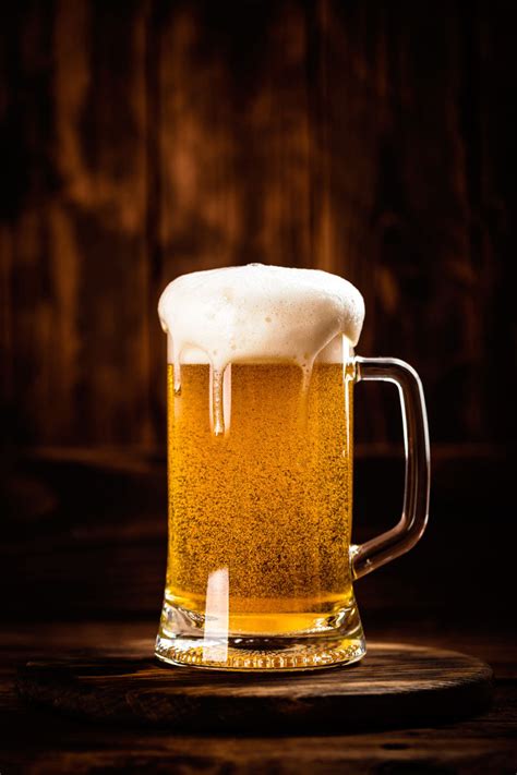 一瓶啤酒和装满啤酒的玻璃杯图片褐色背景下木桌上的一瓶啤酒和装满啤酒的玻璃杯素材高清图片摄影照片寻图免费打包下载