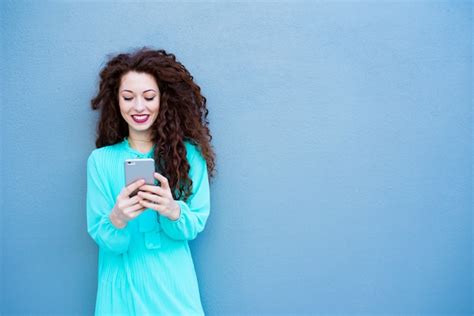 Mulher Jovem Feliz No Telefone Celular Em Uma Parede Azul Foto Premium
