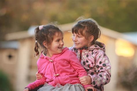 Outdoor Portrait Of Two Young Happy Children Girls Sisters Stock
