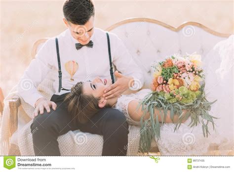 The Close Up Portrait Of The Groom Petting The Face Of The Lying On His