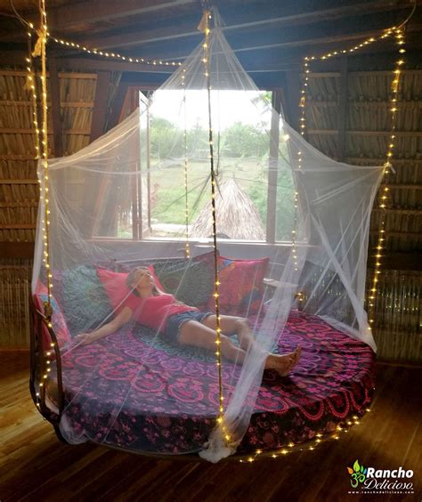A Woman Laying On Top Of A Bed Covered In Mosquito Netting