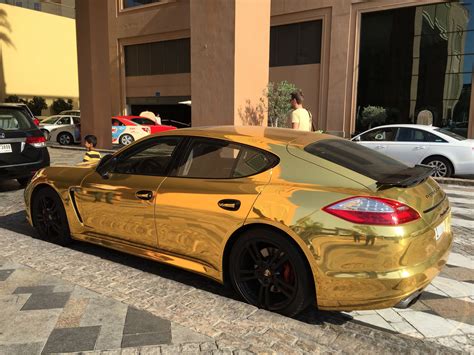 A Gold Sports Car Parked In Front Of A Building