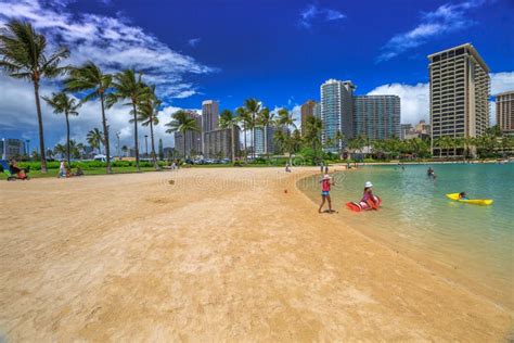 Tourist Sunbathing And Surfing On The Waikiki Beach In Hawaii