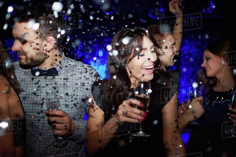 Group Of Friends With Champagne Dancing In Confetti Rain Stock Photo