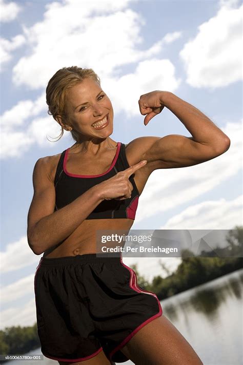 Portrait Of Mature Woman Flexing Muscles Lake In Background High Res