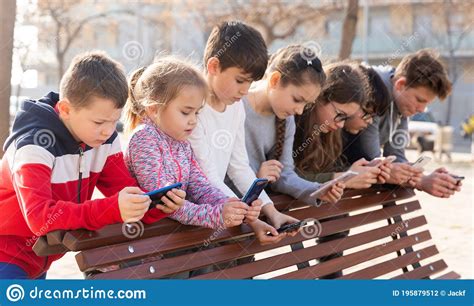 Children Are Playing On Smartphone In The Playground Stock Photo