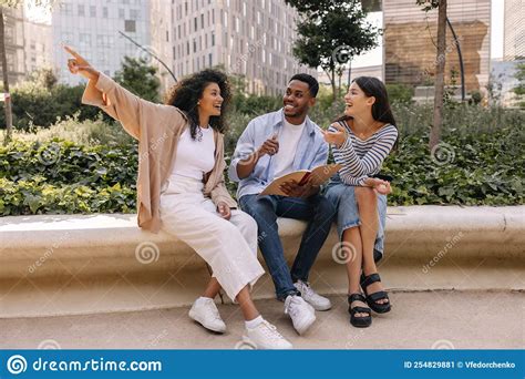 Pretty Young Interracial Classmates Spend Leisure Time Together Sitting Outdoors Stock Image