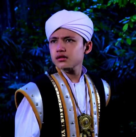 A Young Man Wearing A White Turban And Black Vest Standing In Front Of
