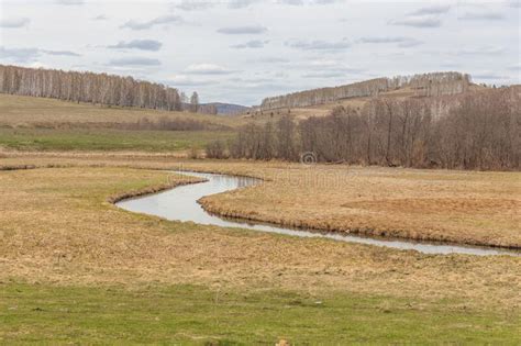 A Small River Flowing Through Meadows And Agricultural Fields Spring