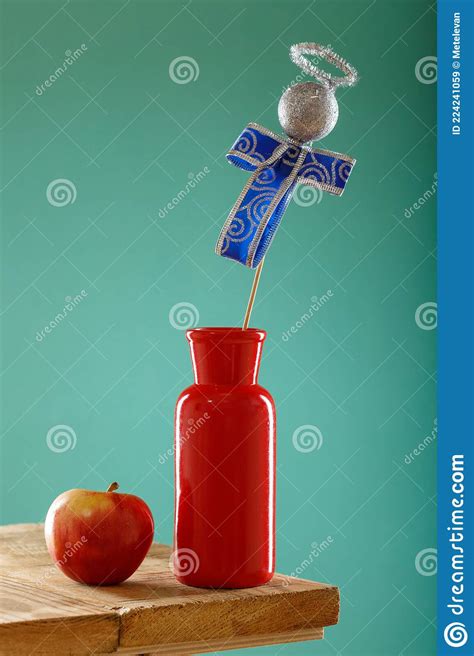 A Red Vase On The Edge Of The Table Next To Her Is An Apple A Wooden