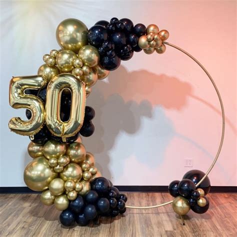 A Balloon Arch With The Number 50 In Gold Black And Silver Balloons Attached To It