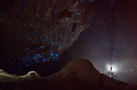 A Man Standing In Front Of A Cave Filled With Blue And White Lights At