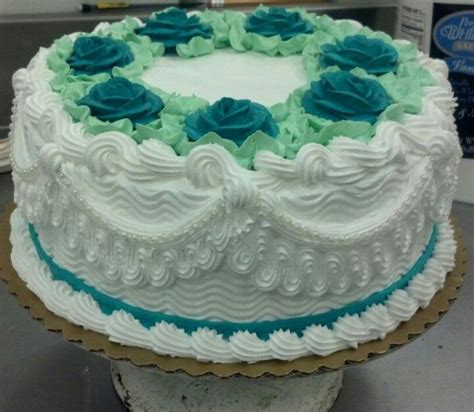 A Cake With White Frosting And Blue Flowers On It Sitting On A Counter Top