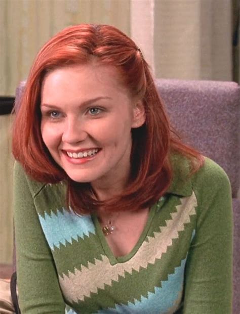 A Woman With Red Hair Sitting On A Couch Smiling At The Camera While