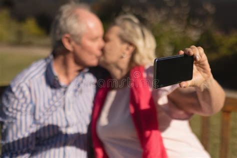 Senior Couple Taking Selfie With Mobile Phone While Kissing Each Other Stock Image Image Of