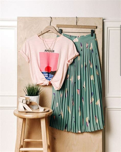 A Pink Shirt And Green Pleated Skirt Are Hanging On A Wooden Hanger