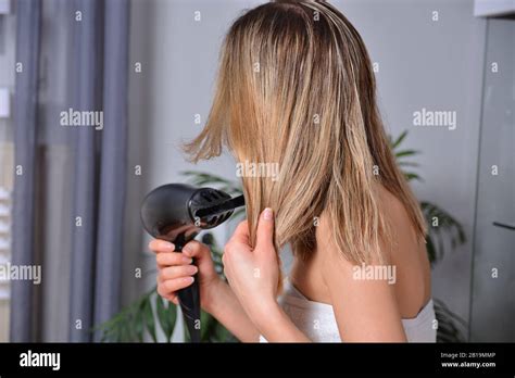 Beautiful Woman Using A Hairdryer And Dries Her Wet Blonde Hair After Showering At Home And Make