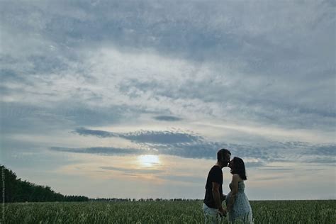 Kissing Couple Silhouette In Front Of Sunset Clouds By Stocksy