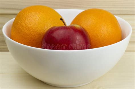 Fresh Juicy Natural Apples And Oranges In A Shiny White Plate On Wooden