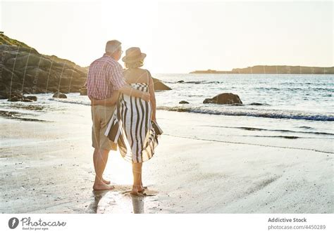 Anonymous Senior Couple Standing On Beach By Waving Sea A Royalty