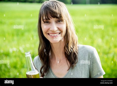 Portrait Of Smiling Brunette Woman With A Beer Bottle Outdoors Stock