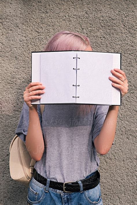girl with pink hair holding open notebook in front of face by stocksy contributor danil