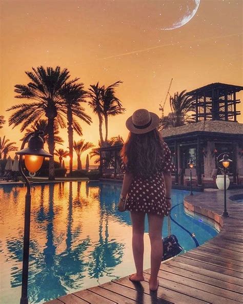 A Woman Is Standing On A Dock Looking At The Water And Palm Trees In
