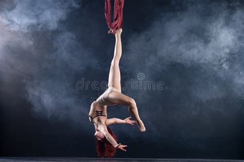 female athletic and flexible aerial circus artist with redhead dancing in the air on the silk