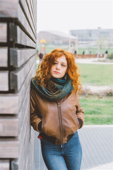 Young Beautiful Redhead Woman Outdoor Looking Camera Leaning Against Wooden Wall Pensive