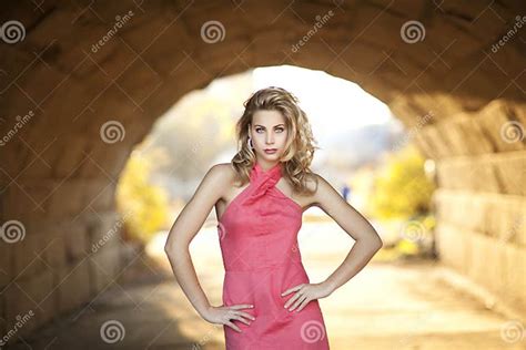 A Tall Blond Woman With Coral Halter Dress In Bright Tunnel Stock