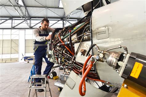 Aircraft Mechanic Repairs An Aircraft Engine In An Airport Hangar Stock