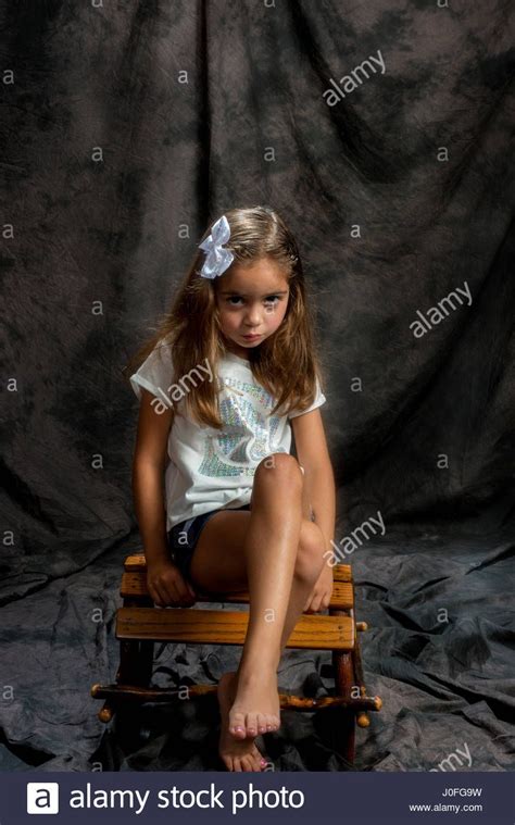 Little Girl Modeling In Studio Brown Background Siting On A Wood Stock