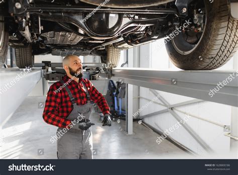 Auto Mechanic Working Underneath Lifted Car Stock Photo 1628800186