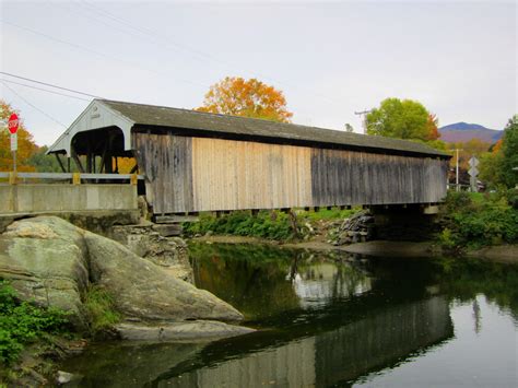 An Old Covered Bridge Over A River In The Fall
