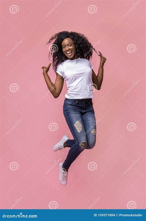 African American Joyful Lady Jumping And Gesturing Peace Stock Photo