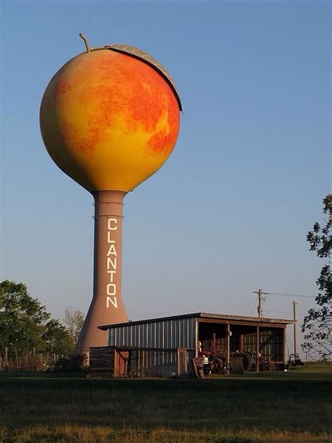 An Orange And Yellow Water Tower Sitting In The Middle Of A Field Next
